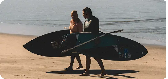 Two SUP surfers carrying their boards on the beach in El Salvador